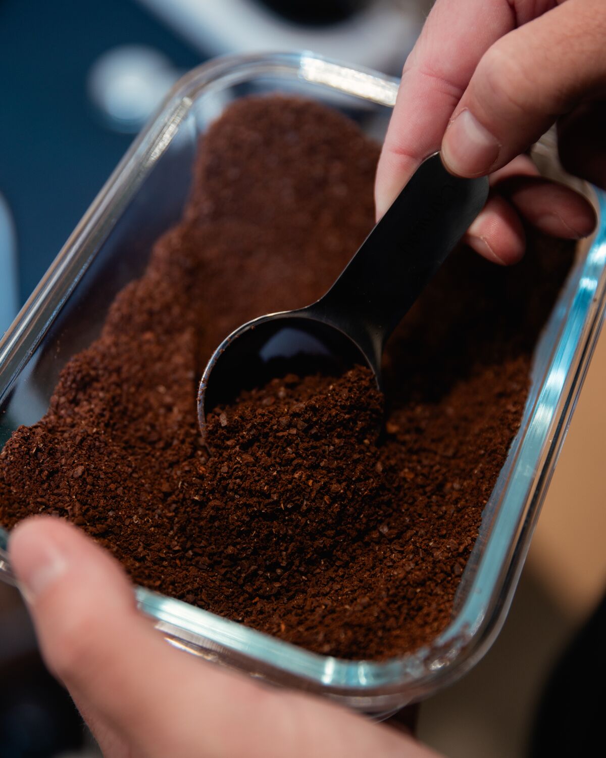 A scoop of freshly ground coffee in a glass container